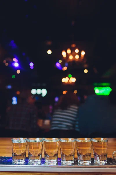 Γυαλιά με ένα αλκοολούχο ποτό σε ένα ξύλινο τραπέζι. — Φωτογραφία Αρχείου