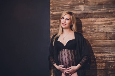 Raslantı giyimli çekici hamile kadın ayakta ev, kamera seyir ve iken gülümseyen