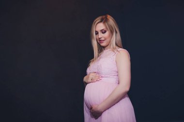 Raslantı giyimli çekici hamile kadın ayakta ev, kamera seyir ve iken gülümseyen