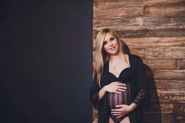 Casualmente vestido mulher grávida atraente em pé em casa, olhando câmera e sorrindo enquanto — Fotografia de Stock