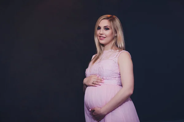 Niedbale ubrany atrakcyjna kobieta w ciąży stałego domu, patrząc aparatu i uśmiechając się, podczas gdy — Zdjęcie stockowe