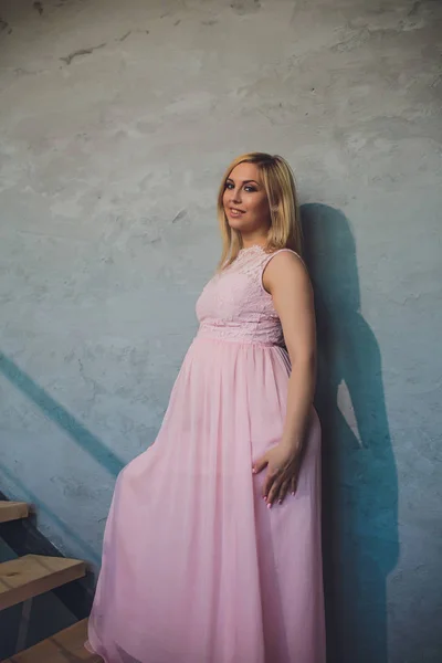 Raslantı giyimli çekici hamile kadın ayakta ev, kamera seyir ve iken gülümseyen — Stok fotoğraf