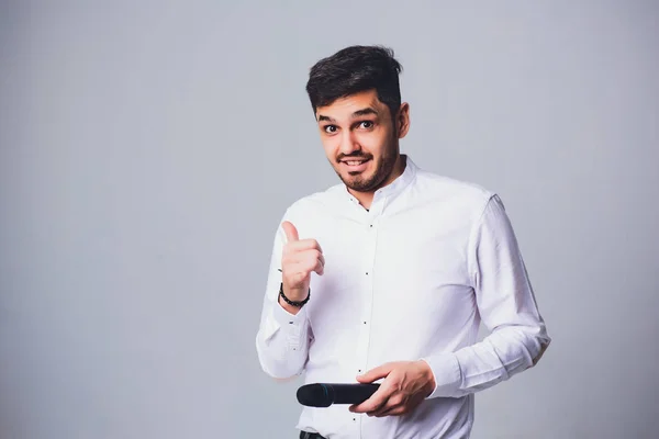 Showman interviewer met emoties. Elegante jongeman microfoon te houden tegen de witte achtergrond. Showman concept. — Stockfoto