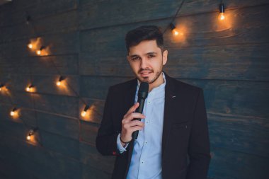 Şovmen görüşmeci duygularla. Beyaz arka plan üzerinde mikrofon tutan zarif delikanlı. Şovmen kavramı.