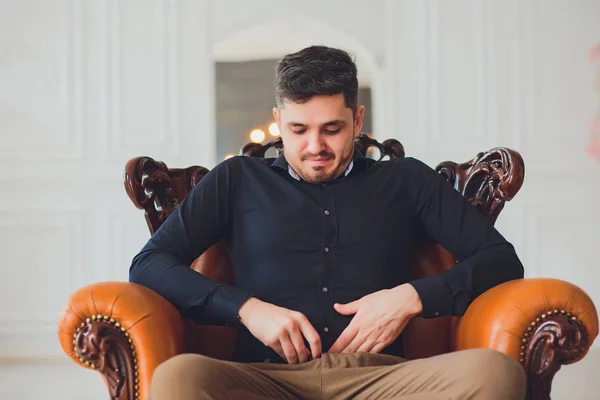 Man zit op de Bank rechtmaakt zijn broek broek — Stockfoto