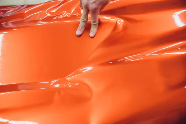 Auto wrapping specialist aanbrengen van vinyl folie of film op auto inwikkeling beschermfolie jacht, boot, schip, auto, mobile home. Oranje film hand trekt — Stockfoto