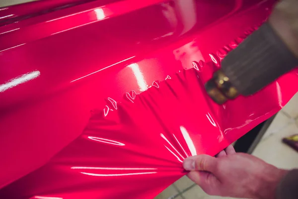 Αυτοκίνητο ειδικός αναδίπλωσης βάζοντας βινυλίου αλουμινόχαρτο ή μεμβράνη στο αυτοκίνητο περιτυλίγματος προστατευτικό φιλμ γιοτ, πλοίο, αυτοκίνητο, σκάφος, κινητό σπίτι. ροζ ταινία κόκκινο χέρι τραβά — Φωτογραφία Αρχείου