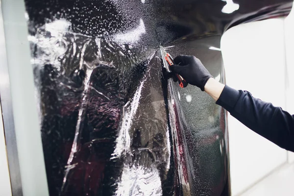 Применение тонирующей фольги на окне автомобиля в гараже — стоковое фото
