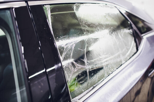 Применение тонирующей фольги на окне автомобиля в гараже
