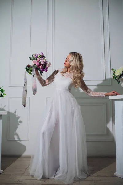 Jovencita bonita. Mujer rubia con pelo rizado largo de lujo. Novia mañana. Tomando el ramo de boda en las manos — Foto de Stock