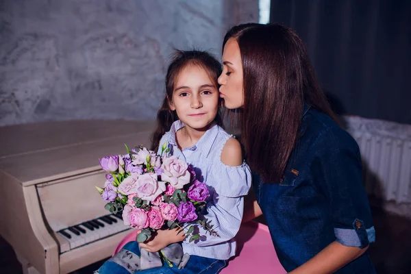 Mooie jonge moeder en haar schattig dochtertje zijn camera kijken en glimlachen. — Stockfoto