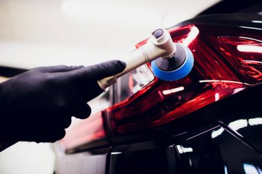 Car polish wax worker hands holding polisher and polish car detailing or valeting concept taillight red car clipart