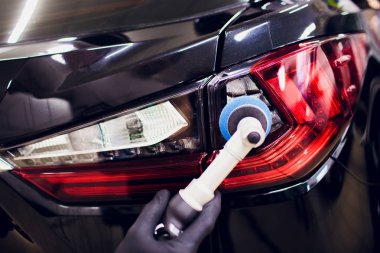 Araba Perdah holding balmumu işçisi eller Lehçe ve Lehçe araba ayrıntılı veya valeting kavramı stop lambası kırmızı araba