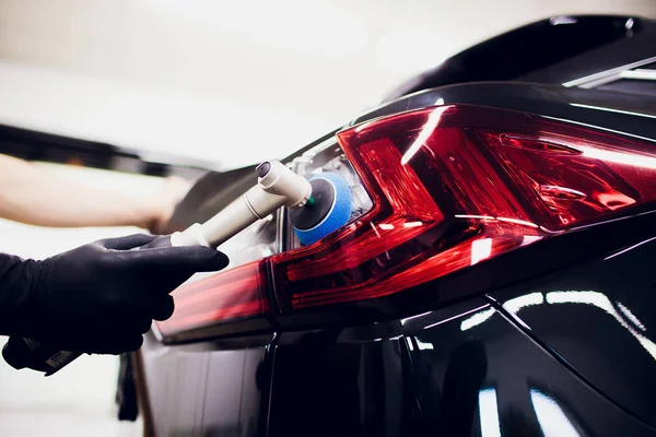 Manos de trabajador de cera pulida del coche que sostienen el pulidor y pule el coche que detalla o valeting concepto luz trasera coche rojo — Foto de Stock