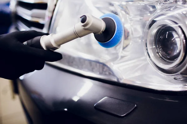 Manos de trabajador de cera pulida del coche que sostienen el pulidor y pule el coche que detalla o valeting concepto delantero blanco auto faro — Foto de Stock