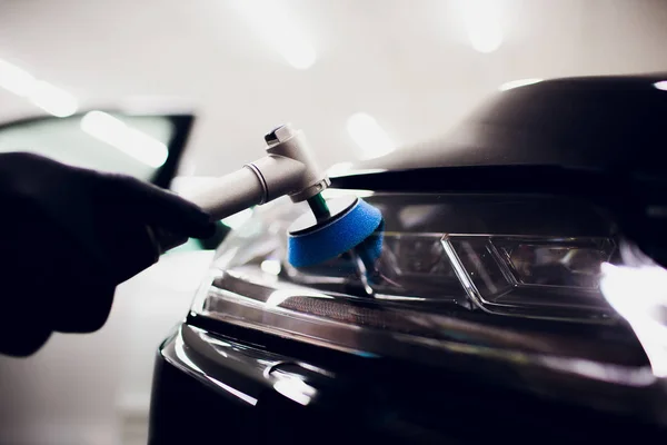 Manos de trabajador de cera pulida del coche que sostienen el pulidor y pule el coche que detalla o valeting concepto delantero blanco auto faro — Foto de Stock