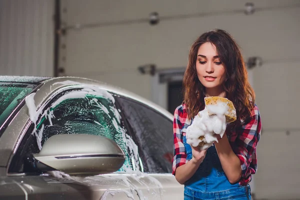 Lavagem de carro ao ar livre com esponja amarela. Menina bonita lava carro — Fotografia de Stock