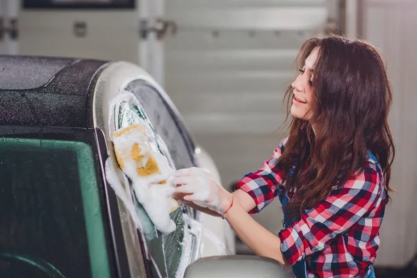 outdoor car wash with yellow sponge. Beautiful girl washes car