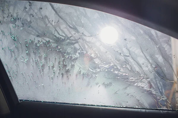 Attractive woman washing automobile manual car washing self service,cleaning with foam,pressured water. Washing car in self service station with high pressure blaster window viewed from inside car — Stock Photo, Image