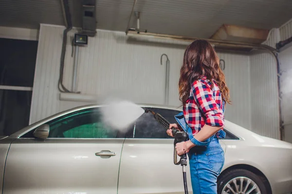 Attractive woman washing automobile manual car washing self service,cleaning with foam,pressured water. Transportation care concept. Washing car in self service station with high pressure blaster