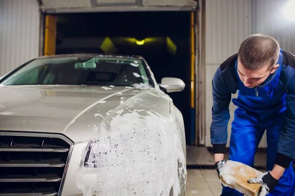 Outdoor car wash with yellow sponge. Beautiful man washes car — Stock Photo, Image