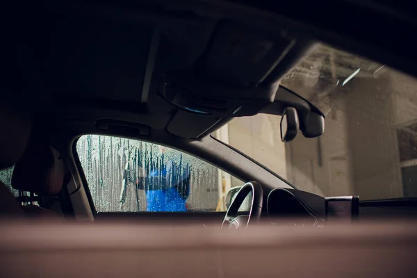 Hombre lavado de automóviles manual de auto lavado de autoservicio, limpieza con espuma, agua a presión. Lavado de coches en la estación de autoservicio con ventanilla de alta presión visto desde el interior del coche — Foto de Stock
