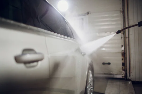 man washing automobile manual car washing self service,cleaning with foam,pressured water. Transportation care concept. Washing car in self service station with high pressure blaster