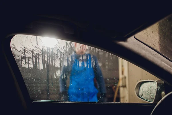 Man washing automobile manual car washing self service,cleaning with foam,pressured water. Washing car in self service station with high pressure blaster window viewed from inside car — Stock Photo, Image