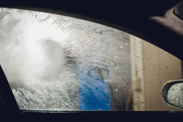 Człowiek mycie samochodów samochód ręczne mycie samoobsługi, czyszczenie pianą, pod presją wody. Mycie samochodu w własnej stacji paliw z wysokiego ciśnienia blaster okno patrząc od wewnątrz samochodu — Zdjęcie stockowe