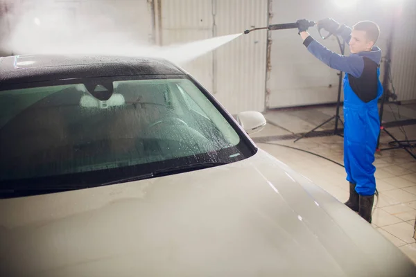 man washing automobile manual car washing self service,cleaning with foam,pressured water. Transportation care concept. Washing car in self service station with high pressure blaster