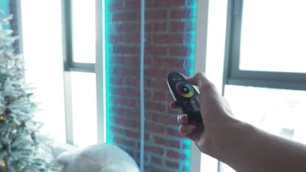 Mano utilizzando un telecomando a luce LED, cambiando e pedalando attraverso il colore delle luci primo piano. muro, mattoni, interno, soppalco — Video Stock