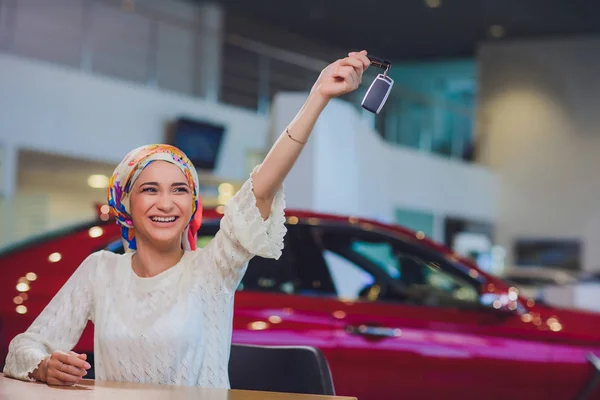 Hermosa mujer disfrutando del momento feliz de conseguir la llave del coche del vendedor de automóviles salón. mujer musulmana en hijab —  Fotos de Stock