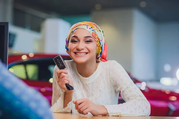 Hermosa mujer disfrutando del momento feliz de conseguir la llave del coche del vendedor de automóviles salón. mujer musulmana en hijab — Foto de Stock