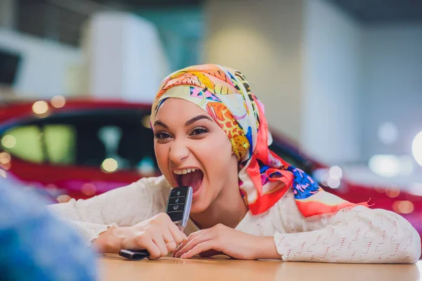 Hermosa mujer disfrutando del momento feliz de conseguir la llave del coche del vendedor de automóviles salón. mujer musulmana en hiyab tontos alrededor — Foto de Stock