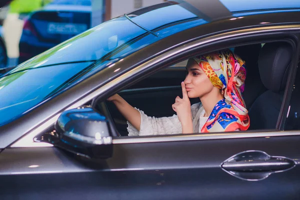 Propiedad y el concepto de la gente - mujer musulmana en hijab con la llave del coche sobre el fondo del espectáculo de coches. mujer feliz tomando la llave del coche del distribuidor en el espectáculo auto o salón — Foto de Stock