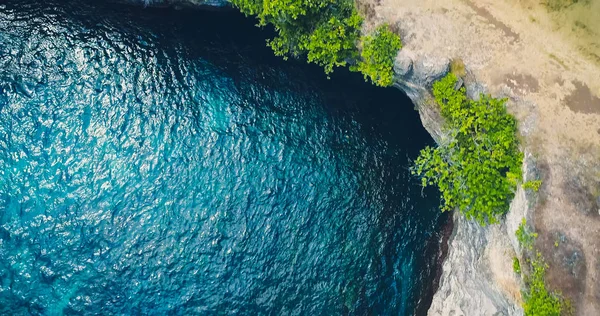 Drone view ocean with waves hitting the rocks on the seashore