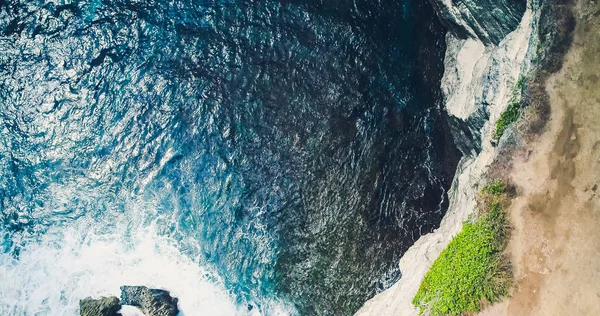 Drone view ocean with waves hitting the rocks on the seashore