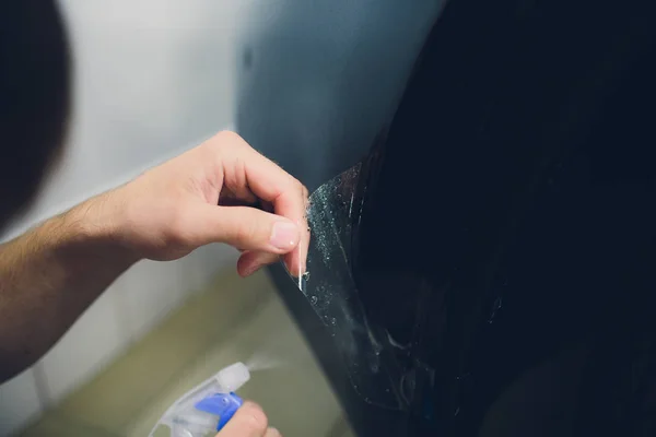 Manos de trabajador instala película de protección de pintura de coche — Foto de Stock