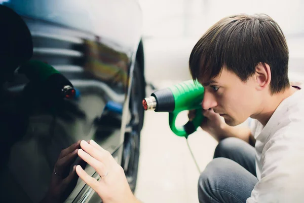 Master nainstaluje odstín film pro auta s vysoušečem vlasů. Koncepce ochrany auto — Stock fotografie