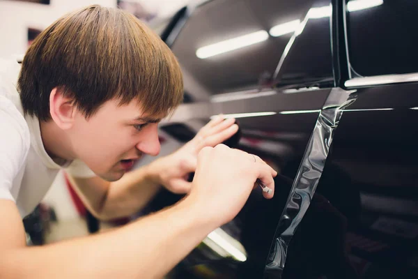 Manos de trabajador instala película de protección de pintura de coche — Foto de Stock