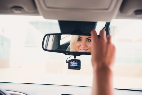 Happy smiling female rejoicing in new expensive purchase in auto showroom. Beautiful customer sitting on door of white folding top car. — Stock Photo, Image