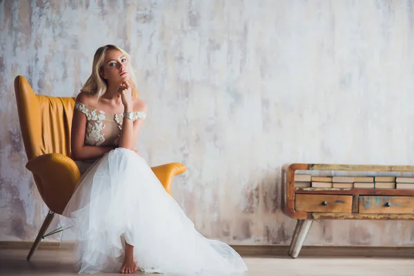 Fille dans la robe, à côté de la librairie, fille dans l'intérieur moderne se trouve sur la chaise — Photo