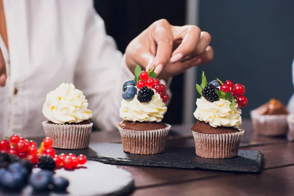 Confiseur décorant cupcake supérieur avec groseille glacée avant de servir — Photo