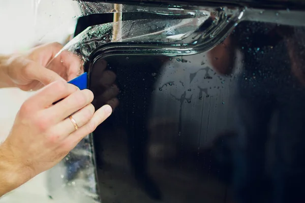 Manos de trabajador instala película de protección de pintura de coche envoltura . — Foto de Stock