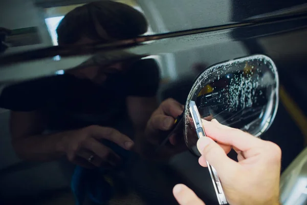 Manos de trabajador instala película de protección de pintura de coche envoltura . — Foto de Stock