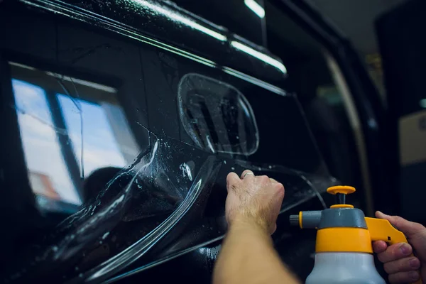 Руки працівника встановлюють захисну плівку для фарби автомобіля . — стокове фото
