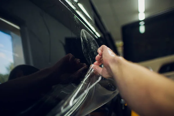 Mani lavoratore installa pellicola di protezione vernice auto avvolgere . — Foto Stock