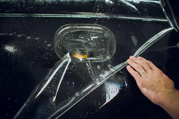 Εργαζόμενος χέρια εγκαθιστά αυτοκίνητο paint προστασίας ταινία αναδιπλώνονται. — Φωτογραφία Αρχείου