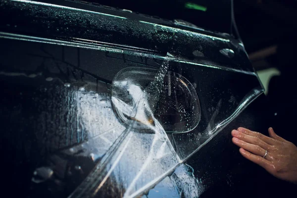 Εργαζόμενος χέρια εγκαθιστά αυτοκίνητο paint προστασίας ταινία αναδιπλώνονται. — Φωτογραφία Αρχείου