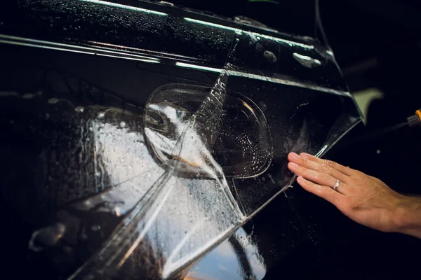 Manos de trabajador instala película de protección de pintura de coche envoltura . — Foto de Stock